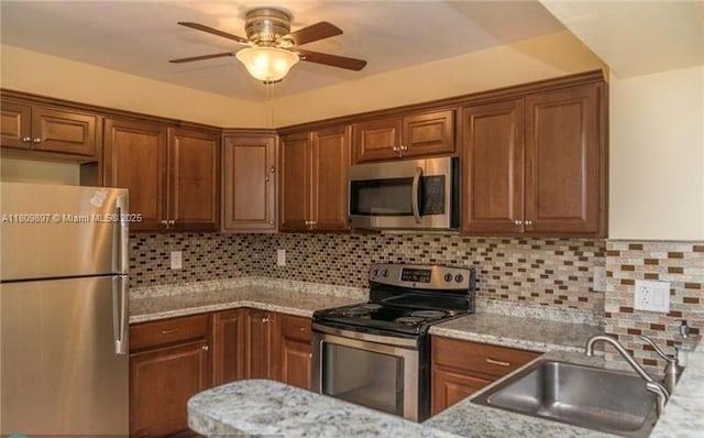 1215-1217 NE 16th Ave, Fort Lauderdale, FL 33304 - kitchen featuring appliances with stainless steel finishes, a sink, ceiling fan, and brown cabinetry