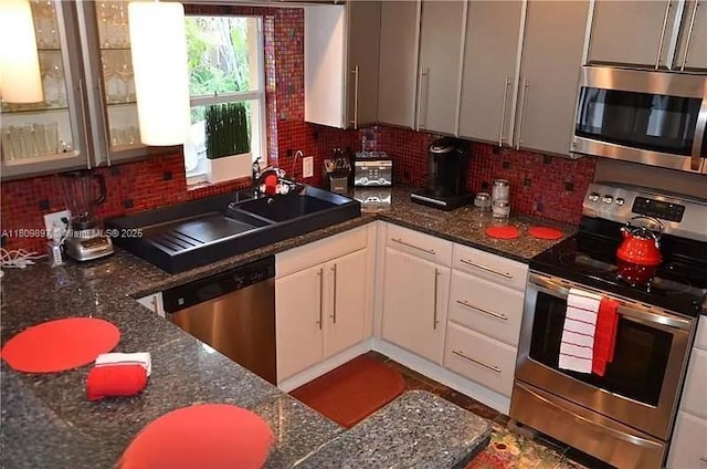 1215-1217 NE 16th Ave, Fort Lauderdale, FL 33304 - kitchen featuring appliances with stainless steel finishes, tasteful backsplash, a sink, white cabinets, and glass insert cabinets