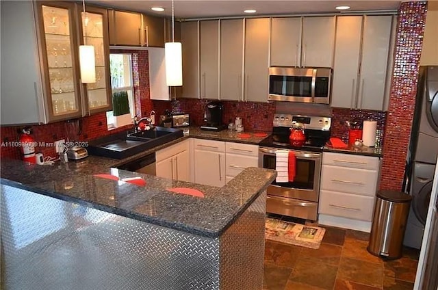 1215-1217 NE 16th Ave, Fort Lauderdale, FL 33304 - kitchen featuring stainless steel appliances, stacked washer / drying machine, a peninsula, and backsplash
