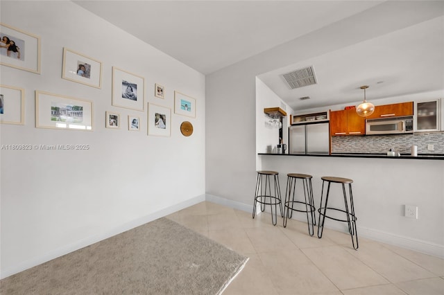 3131 NE 188th St Unit 2-506, Aventura, FL 33180 - kitchen featuring stainless steel appliances, brown cabinets, a kitchen bar, dark countertops, and decorative backsplash