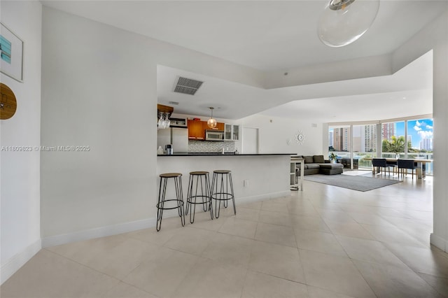 3131 NE 188th St Unit 2-506, Aventura, FL 33180 - kitchen with appliances with stainless steel finishes, backsplash, dark countertops, a breakfast bar area, and a peninsula