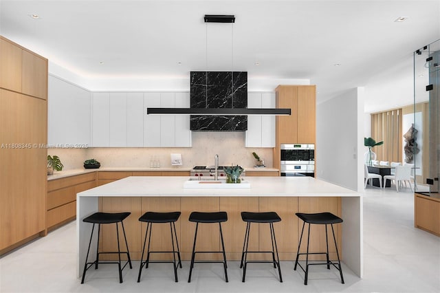 11001 SW 65th Ave, Pinecrest, FL 33156 - kitchen featuring modern cabinets, backsplash, light countertops, and a breakfast bar