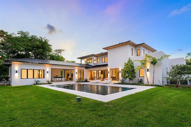 11001 SW 65th Ave, Pinecrest, FL 33156 - rear view of property featuring stucco siding, an outdoor pool, a lawn, and a patio