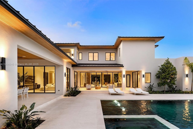 11001 SW 65th Ave, Pinecrest, FL 33156 - back of house with a patio, a standing seam roof, stucco siding, a metal roof, and a pool with connected hot tub