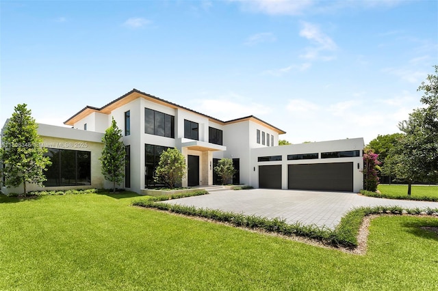 11001 SW 65th Ave, Pinecrest, FL 33156 - contemporary home with stucco siding, an attached garage, decorative driveway, and a front yard