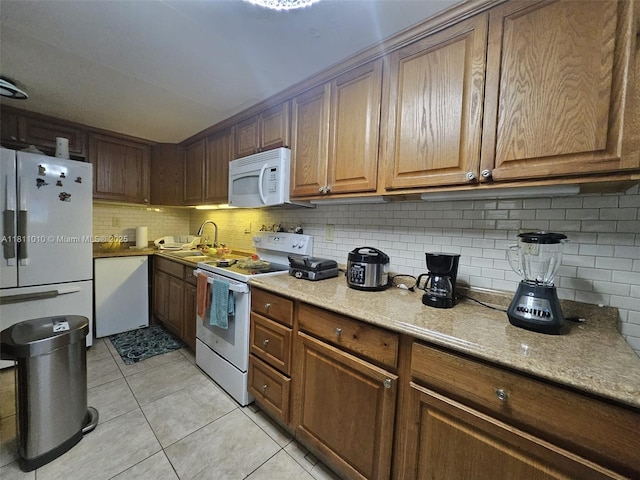 2848 W Marina Dr, Dania Beach, FL 33312 - kitchen with white appliances, tasteful backsplash, light tile patterned floors, a sink, and brown cabinets