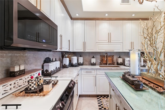 1805 Ponce De Leon Blvd Unit 1200, Coral Gables, FL 33134 - kitchen featuring stainless steel microwave, a sink, white cabinets, tasteful backsplash, and light tile patterned floors