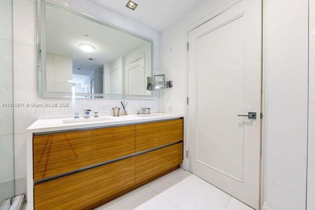 901 Brickell Key Blvd Unit 906, Miami, FL 33131 - bathroom with double vanity, tile patterned flooring, and a shower with shower door