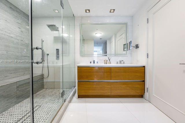 901 Brickell Key Blvd Unit 906, Miami, FL 33131 - full bathroom featuring double vanity, a stall shower, and tile patterned flooring