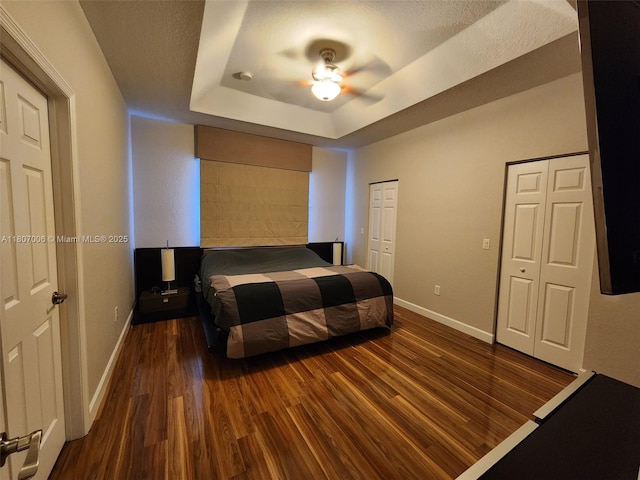 11249 NW 87th Ter, Doral, FL 33178 - bedroom featuring baseboards, dark wood-style floors, a tray ceiling, and a ceiling fan