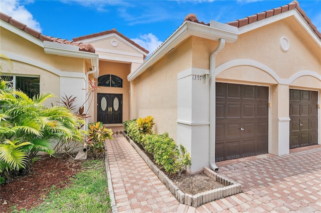 1357 Camellia Ln, Weston, FL 33326 - entrance to property featuring decorative driveway, a garage, stucco siding, and a tiled roof