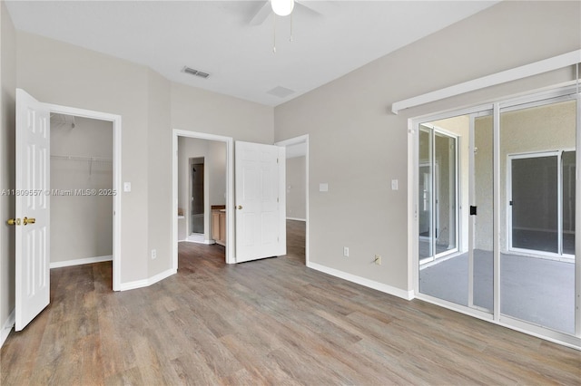 7974 Niagara Falls Ct, Orlando, FL 32825 - unfurnished bedroom featuring wood finished floors, a walk in closet, baseboards, a closet, and a ceiling fan