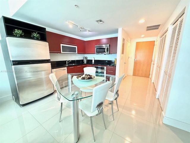 253 NE 2nd St Unit 625, Miami, FL 33132 - kitchen with stainless steel appliances, dark countertops, a sink, light tile patterned flooring, and reddish brown cabinets