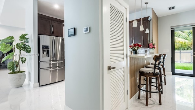 19120 SW 127th Pl, Miami, FL 33177 - kitchen with stainless steel refrigerator with ice dispenser, light marble finish floors, a kitchen bar, dark brown cabinetry, and tasteful backsplash