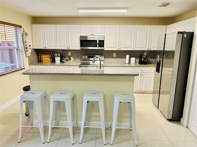 15222 SW 30th Ter, Miami, FL 33185 - kitchen with stainless steel appliances, light tile patterned floors, white cabinetry, and a kitchen breakfast bar