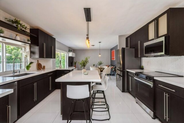7625 SW 108th Ter, Pinecrest, FL 33156 - kitchen with appliances with stainless steel finishes, a sink, light countertops, open shelves, and backsplash