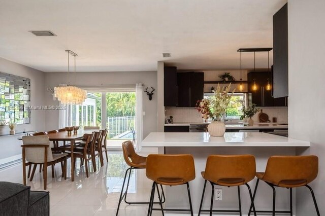 7625 SW 108th Ter, Pinecrest, FL 33156 - kitchen featuring a chandelier, light countertops, a breakfast bar, tasteful backsplash, and decorative light fixtures