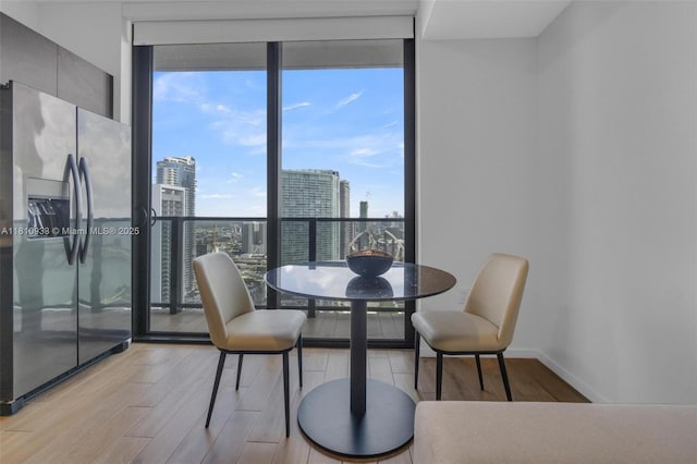 398 NE 5th St Unit 3803, Miami, FL 33132 - dining space featuring floor to ceiling windows, wood finished floors, a city view, and baseboards