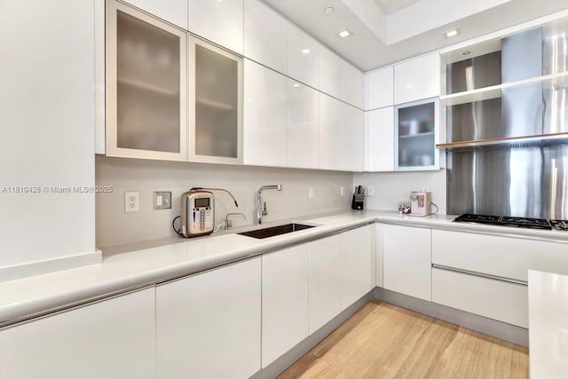 9701 Collins Ave Unit 2403S, Bal Harbour, FL 33154 - kitchen featuring a sink, light countertops, wall chimney range hood, and white cabinetry