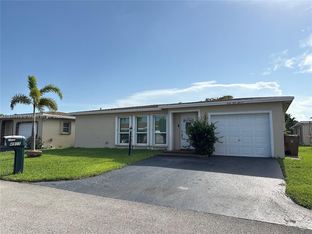 4911 NW 14th Ave, Deerfield Beach, FL 33064 - ranch-style home with stucco siding, a garage, driveway, and a front lawn