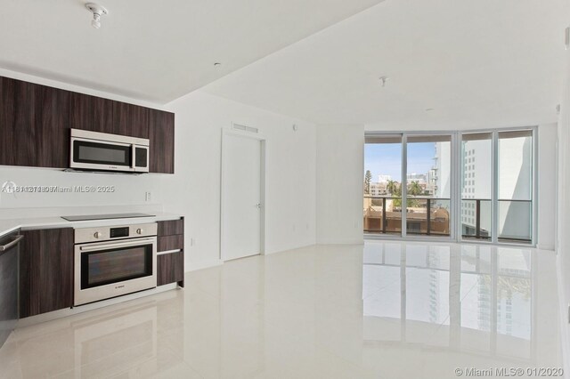488 NE 18th St Unit 501, Miami, FL 33132 - kitchen featuring oven, stainless steel microwave, modern cabinets, light tile patterned flooring, and black electric stovetop