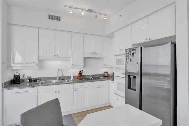 4779 Collins Ave Unit 4006, Miami Beach, FL 33140 - kitchen featuring white appliances, a sink, white cabinets, under cabinet range hood, and stone countertops