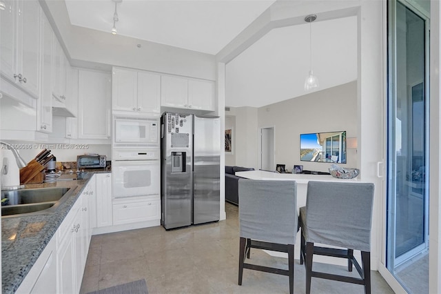 4779 Collins Ave Unit 4006, Miami Beach, FL 33140 - kitchen with white appliances, white cabinetry, a sink, under cabinet range hood, and decorative light fixtures