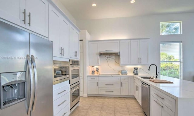 5342 SW 173rd Ave, Miramar, FL 33029 - kitchen featuring stainless steel appliances, a sink, a peninsula, under cabinet range hood, and tasteful backsplash