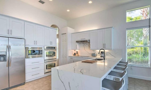 5342 SW 173rd Ave, Miramar, FL 33029 - kitchen featuring stainless steel appliances, a sink, light stone counters, under cabinet range hood, and a peninsula