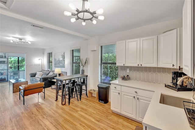 2763 NW 3rd St, Miami, FL 33125 - kitchen with open floor plan, light countertops, a chandelier, decorative backsplash, and white cabinets