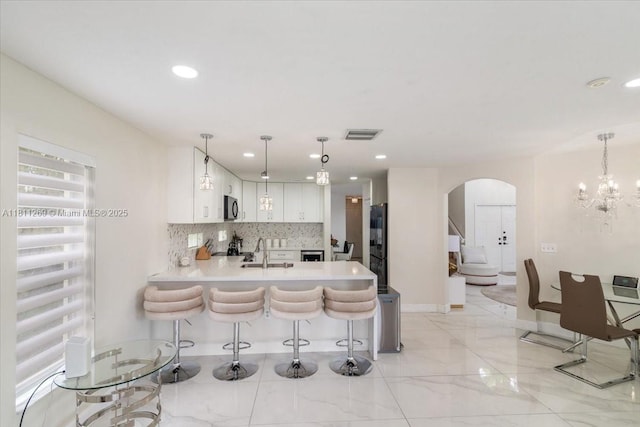 16466 SW 29th St, Miramar, FL 33027 - kitchen featuring a sink, arched walkways, backsplash, freestanding refrigerator, and a peninsula