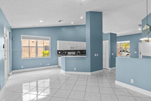 930 Briar Ridge Rd, Weston, FL 33327 - kitchen with white microwave, lofted ceiling, white cabinets, a textured ceiling, and light tile patterned flooring