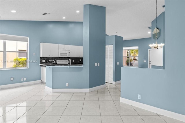 930 Briar Ridge Rd, Weston, FL 33327 - kitchen with white microwave, white cabinetry, baseboards, pendant lighting, and light tile patterned floors