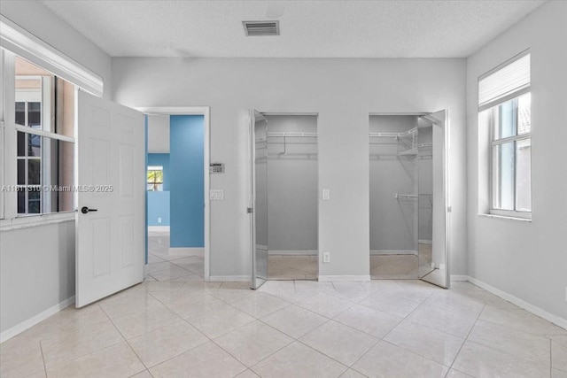 930 Briar Ridge Rd, Weston, FL 33327 - unfurnished bedroom with multiple closets, a textured ceiling, light tile patterned flooring, and baseboards