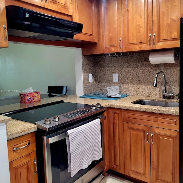 2905 Point E Dr Unit L402, Aventura, FL 33160 - kitchen with stainless steel range with electric cooktop, range hood, a sink, brown cabinetry, and decorative backsplash