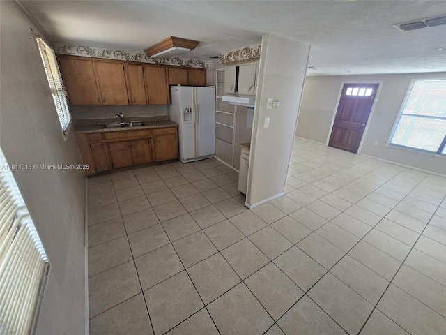 1521 Richmond Rd, Lakeland, FL 33805 - kitchen featuring white refrigerator with ice dispenser, a sink, light tile patterned floors, brown cabinetry, and range hood