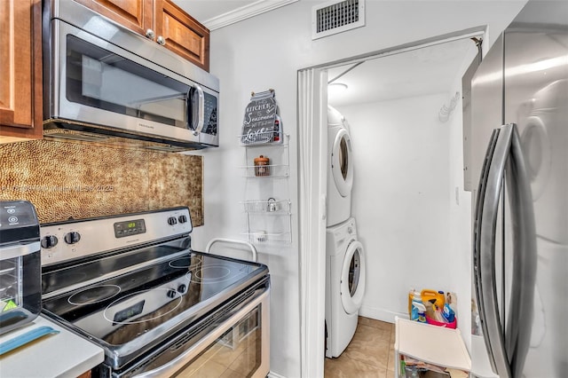 2316 SW 81st Way Unit 8, North Lauderdale, FL 33068 - kitchen with stainless steel appliances, stacked washer / drying machine, brown cabinets, light tile patterned flooring, and ornamental molding