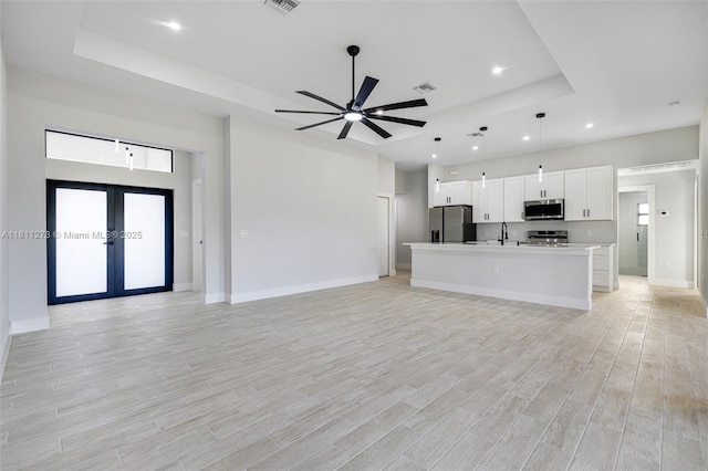2709 58th St W, Lehigh Acres, FL 33971 - unfurnished living room with a tray ceiling, light wood-type flooring, baseboards, french doors, and recessed lighting