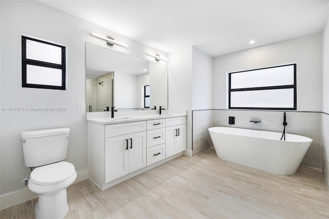 2709 58th St W, Lehigh Acres, FL 33971 - full bathroom with double vanity, a freestanding tub, a tile shower, toilet, and baseboards