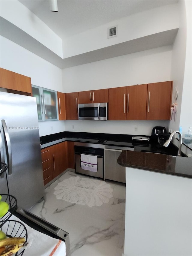 325 S Biscayne Blvd Unit 14, Miami, FL 33131 - kitchen with appliances with stainless steel finishes, a sink, dark countertops, light marble finish floors, and brown cabinetry
