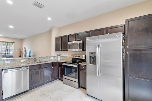 9471 SW 171st Pl, Miami, FL 33196 - kitchen with stainless steel appliances, a sink, light tile patterned floors, dark brown cabinetry, and light stone countertops