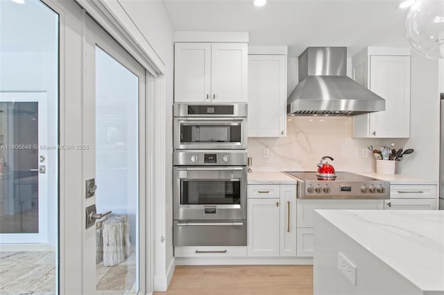 14270 SW 74th Ct, Palmetto Bay, FL 33158 - kitchen with wall chimney range hood, stovetop, a warming drawer, white cabinets, and light stone counters