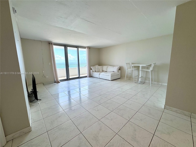 5555 Collins Ave Unit 6E, Miami Beach, FL 33140 - unfurnished living room featuring floor to ceiling windows, baseboards, and light tile patterned floors