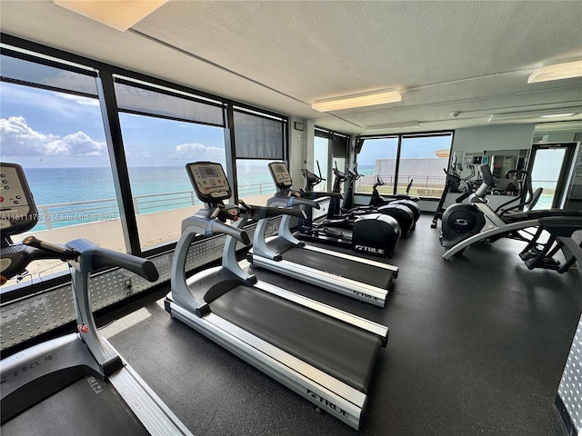5555 Collins Ave Unit 6E, Miami Beach, FL 33140 - exercise room featuring a textured ceiling, a water view, and expansive windows