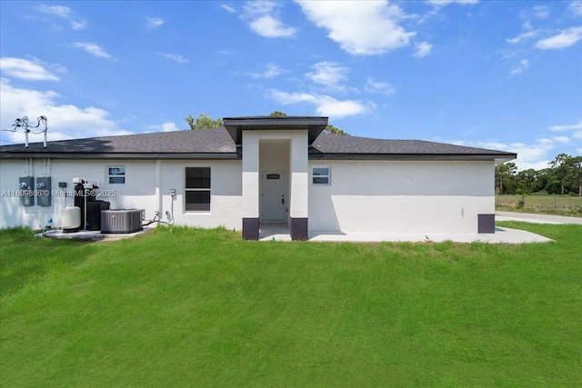 4800 Nelson Dr, Lehigh Acres, FL 33973 - back of property featuring stucco siding, a lawn, roof with shingles, and central AC unit