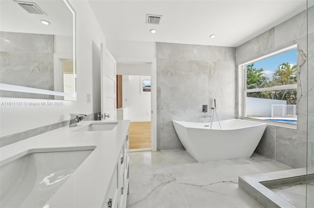 2001 SW 23rd Ave, Fort Lauderdale, FL 33312 - bathroom featuring tile walls, a soaking tub, double vanity, marble tiled floors, and recessed lighting