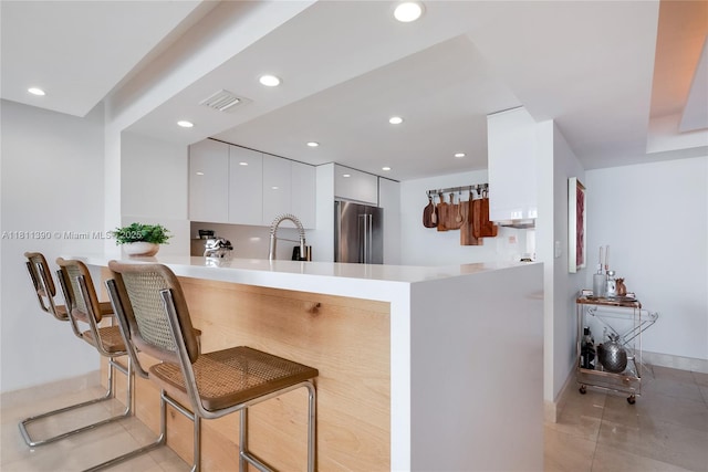 2 Grove Isle Dr Unit B1108, Miami, FL 33133 - kitchen featuring high end refrigerator, modern cabinets, white cabinets, a peninsula, and light tile patterned floors
