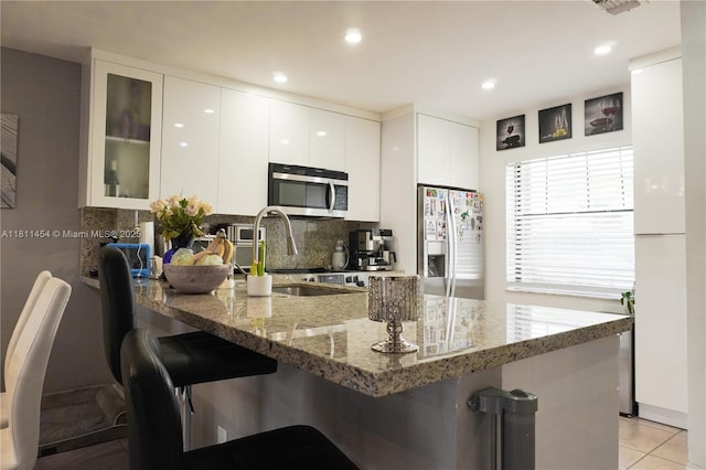 721 NW 105th Ter Unit 721, Pembroke Pines, FL 33026 - kitchen featuring appliances with stainless steel finishes, a peninsula, a breakfast bar, decorative backsplash, and recessed lighting
