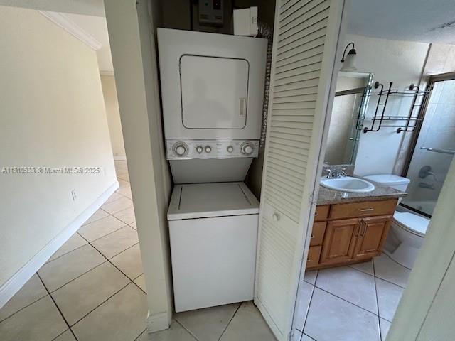8475 SW 94th St Unit 116E, Miami, FL 33156 - laundry area featuring stacked washer / drying machine, light tile patterned floors, and baseboards