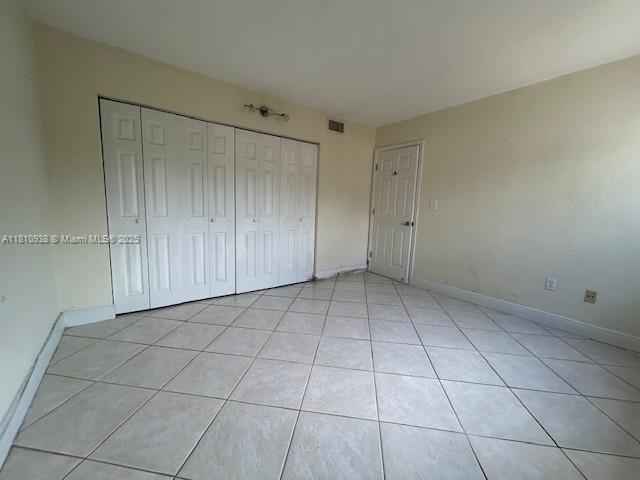 8475 SW 94th St Unit 116E, Miami, FL 33156 - unfurnished bedroom with a closet, baseboards, and light tile patterned flooring